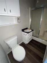 full bathroom featuring a shower stall, toilet, and wood finished floors