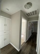 hallway with visible vents, baseboards, and dark wood-type flooring