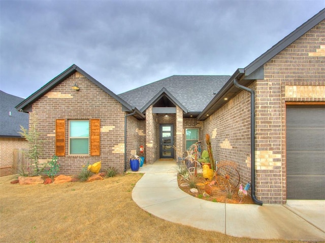 view of front of house with brick siding, an attached garage, and a shingled roof