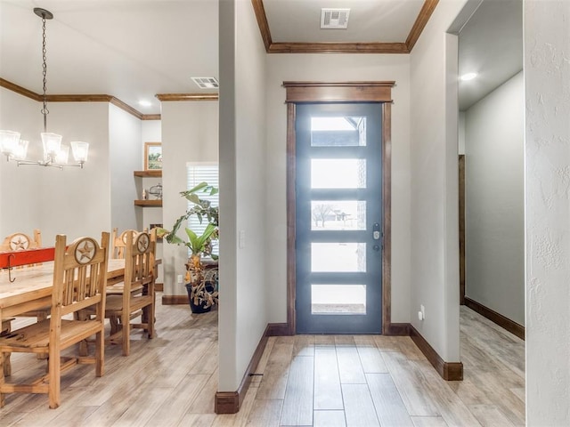 entrance foyer with light wood finished floors, visible vents, crown molding, and an inviting chandelier