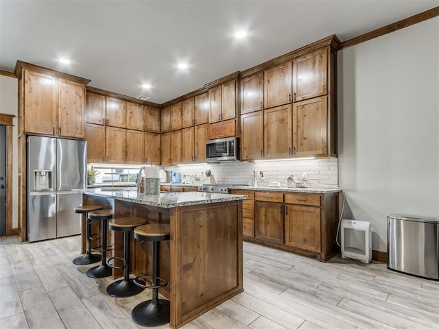 kitchen with decorative backsplash, appliances with stainless steel finishes, wood tiled floor, and light stone countertops