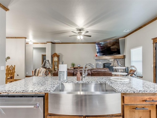 kitchen with visible vents, a sink, open floor plan, a brick fireplace, and ceiling fan