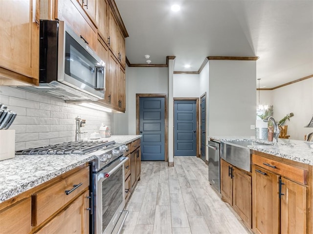 kitchen featuring tasteful backsplash, ornamental molding, light wood-style flooring, stainless steel appliances, and a sink