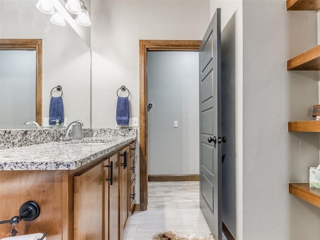 bathroom featuring vanity, wood finished floors, and baseboards