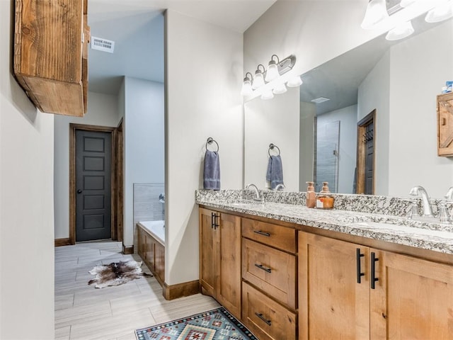 bathroom featuring double vanity, a bath, visible vents, and a sink