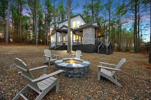 rear view of property featuring a fire pit and stairs