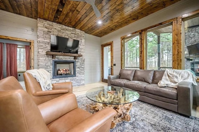 living room with wood finished floors, wooden walls, a fireplace, wood ceiling, and ceiling fan