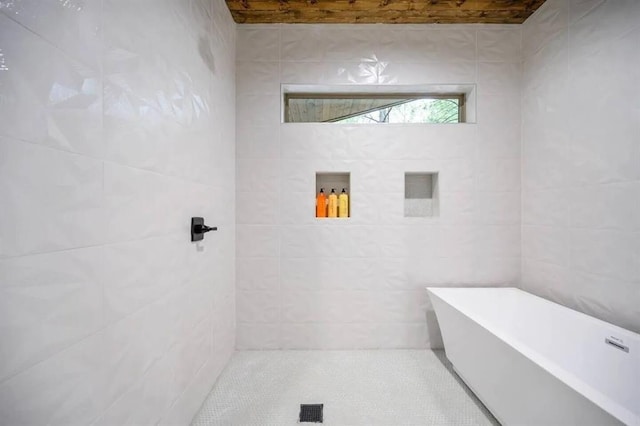 bathroom with a freestanding tub and tile walls