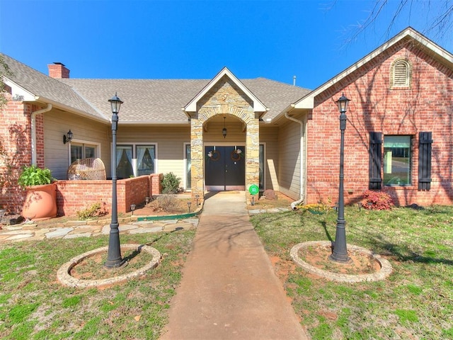 view of front facade featuring brick siding, a front yard, and roof with shingles