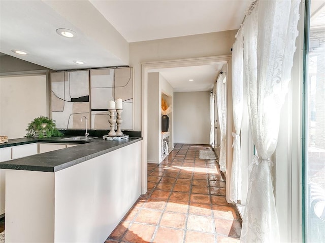 kitchen featuring dark countertops, recessed lighting, white cabinetry, and a sink