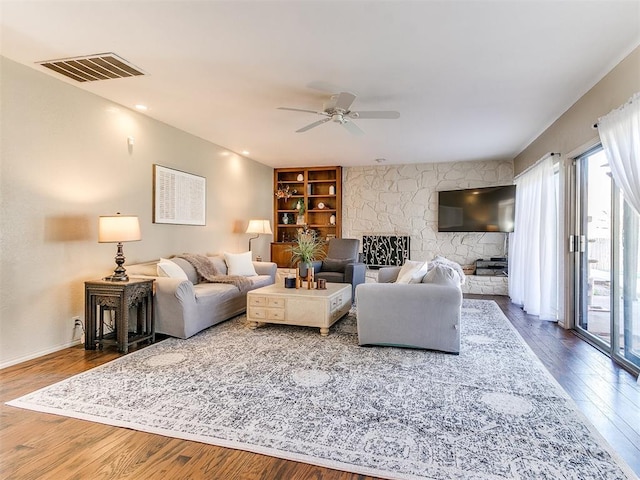 living area featuring ceiling fan, visible vents, wood finished floors, and a fireplace