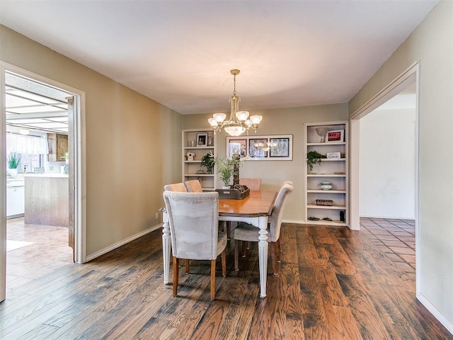 dining space featuring baseboards, dark wood-type flooring, an inviting chandelier, and built in shelves