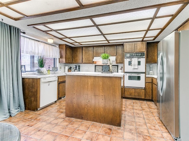 kitchen with white appliances, light tile patterned floors, light countertops, and a kitchen island