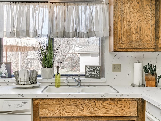 kitchen featuring a sink, brown cabinets, dishwasher, and a healthy amount of sunlight