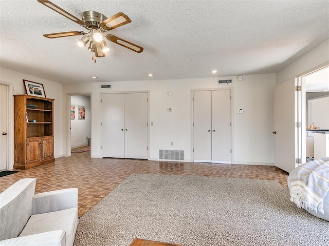 living room with visible vents, a textured ceiling, and ceiling fan