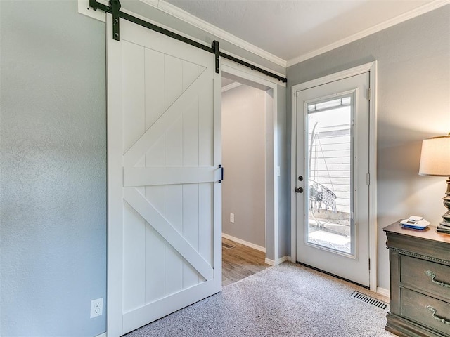 entryway with visible vents, baseboards, a barn door, carpet floors, and ornamental molding