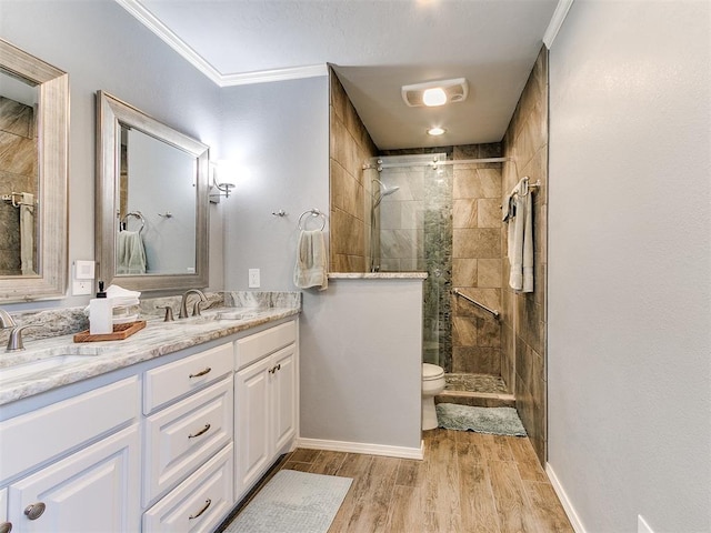 bathroom featuring ornamental molding, a stall shower, wood finished floors, and a sink