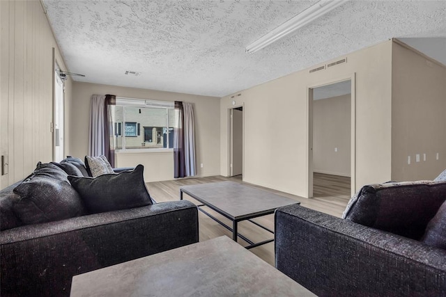 living room with wood finished floors, visible vents, and a textured ceiling