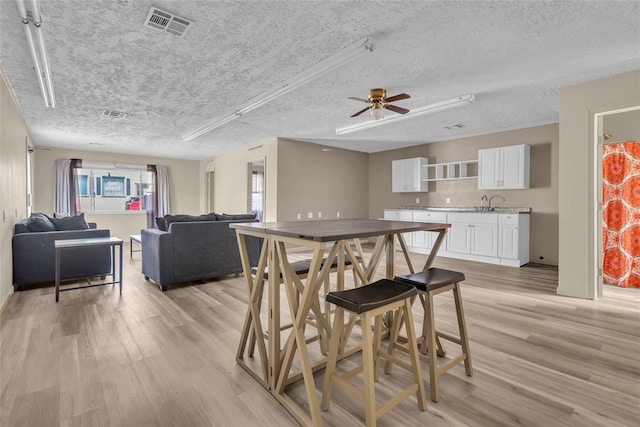 dining space featuring visible vents, a textured ceiling, and light wood finished floors