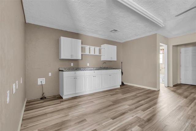 kitchen with visible vents, light wood-type flooring, white cabinets, a textured ceiling, and open shelves