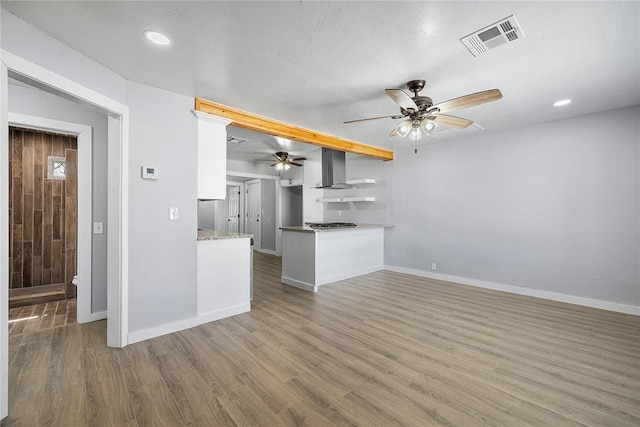 unfurnished living room featuring visible vents, baseboards, a ceiling fan, and wood finished floors