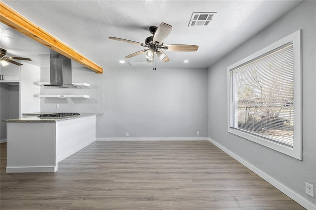 kitchen with open shelves, visible vents, a ceiling fan, and wall chimney range hood