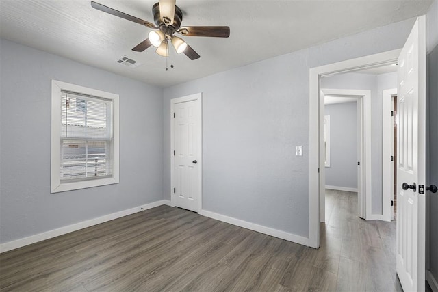 unfurnished bedroom featuring dark wood finished floors, visible vents, and baseboards