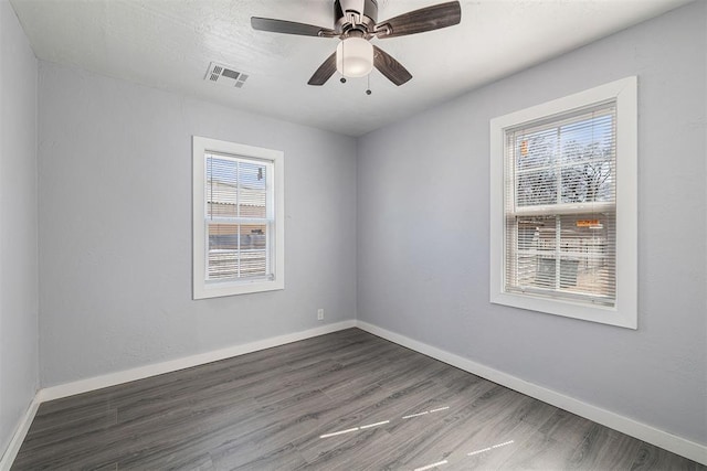 spare room with visible vents, baseboards, wood finished floors, and a ceiling fan