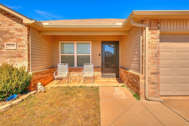 doorway to property with an attached garage and brick siding