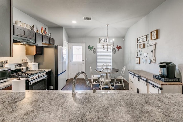 kitchen featuring visible vents, under cabinet range hood, light stone counters, stainless steel appliances, and a chandelier