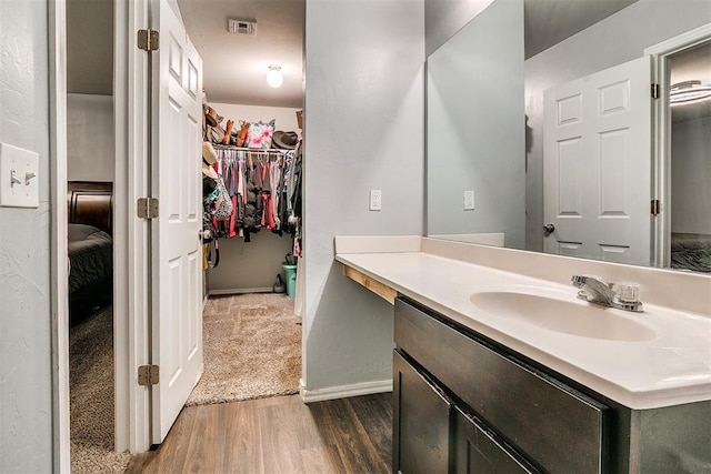 bathroom featuring a spacious closet, visible vents, baseboards, wood finished floors, and vanity