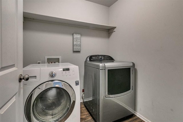 clothes washing area featuring washer and clothes dryer, laundry area, baseboards, and wood finished floors