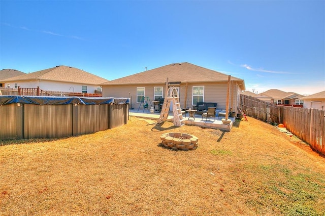 back of property with a fenced in pool, an outdoor fire pit, a lawn, a fenced backyard, and a patio