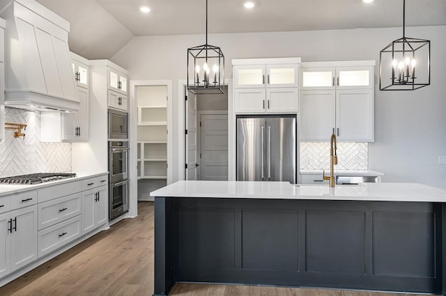 kitchen with white cabinetry, an inviting chandelier, custom range hood, and appliances with stainless steel finishes