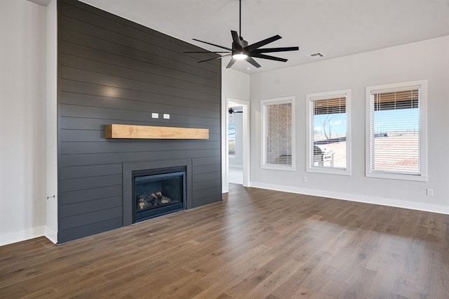 unfurnished living room featuring a fireplace, wood finished floors, a ceiling fan, and visible vents