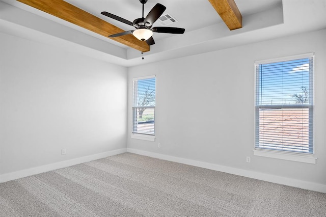 empty room with visible vents, carpet, baseboards, beamed ceiling, and a raised ceiling