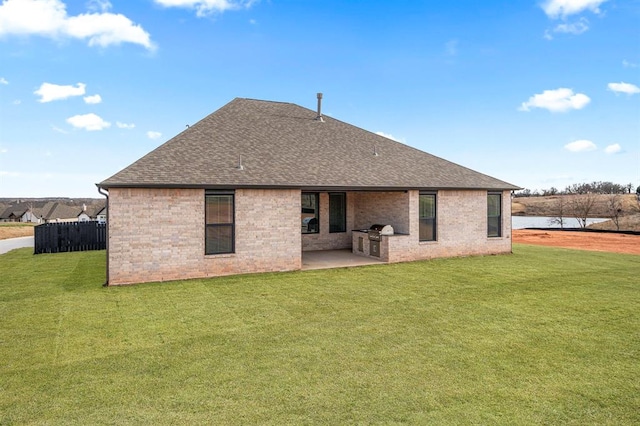 back of property featuring a patio, fence, a yard, a shingled roof, and brick siding