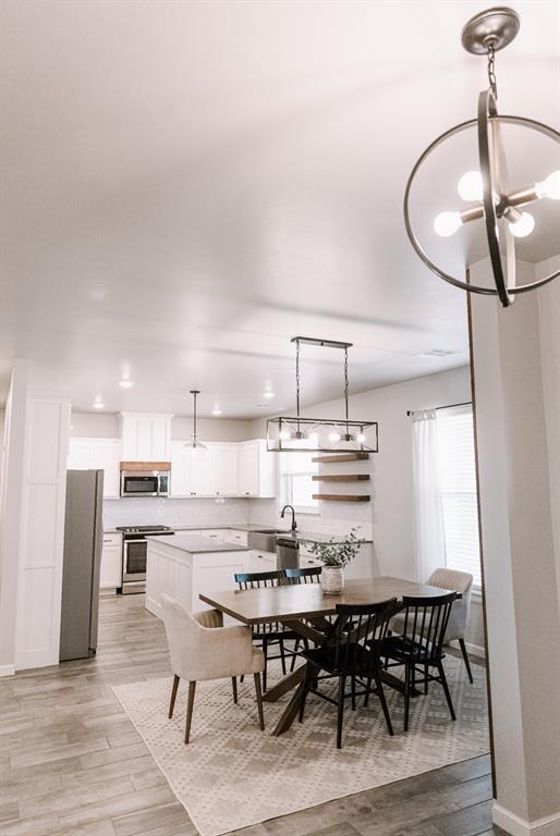 dining room featuring an inviting chandelier, light wood-style floors, and baseboards