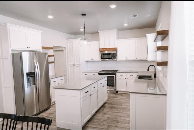 kitchen with visible vents, a sink, a kitchen island, stainless steel appliances, and open shelves