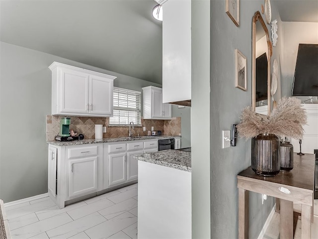 kitchen with light stone countertops, white cabinets, black dishwasher, marble finish floor, and backsplash