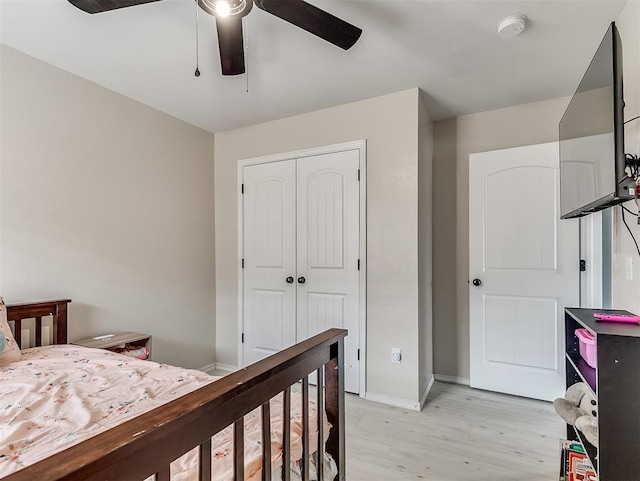 bedroom featuring a closet, light wood-style flooring, a ceiling fan, and baseboards