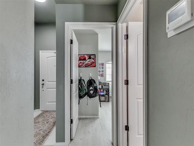 hall featuring a textured wall and light wood-type flooring