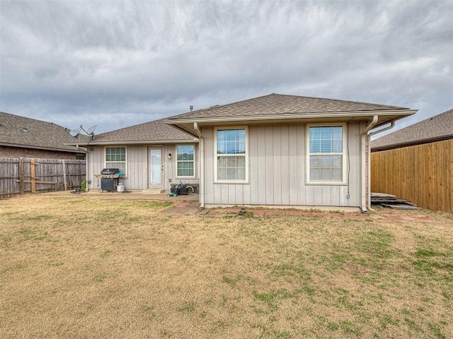 rear view of property with a lawn, a fenced backyard, and roof with shingles