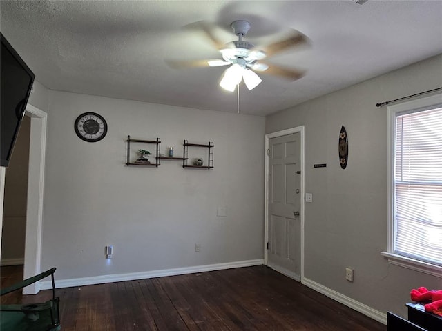 interior space featuring a textured ceiling, baseboards, a ceiling fan, and dark wood-style flooring