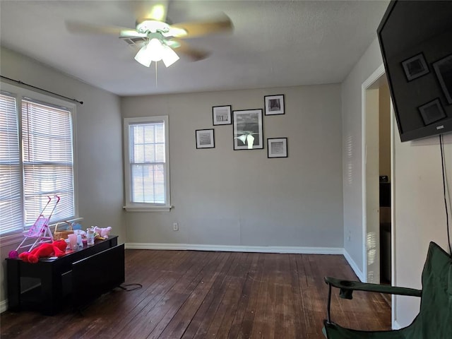 interior space with baseboards, ceiling fan, and wood-type flooring