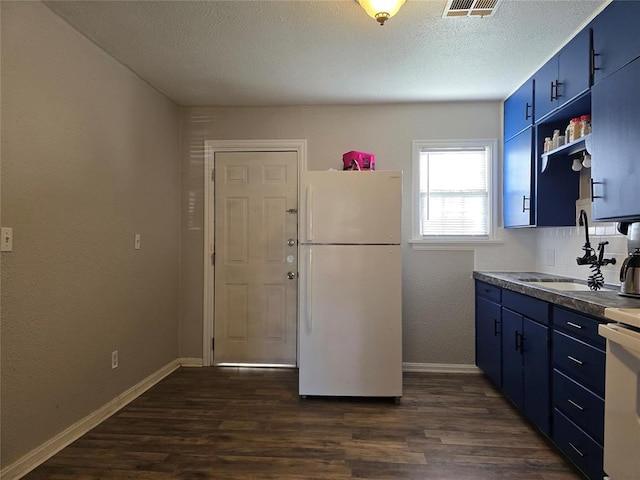 kitchen with blue cabinets, white appliances, dark wood-style flooring, and a sink