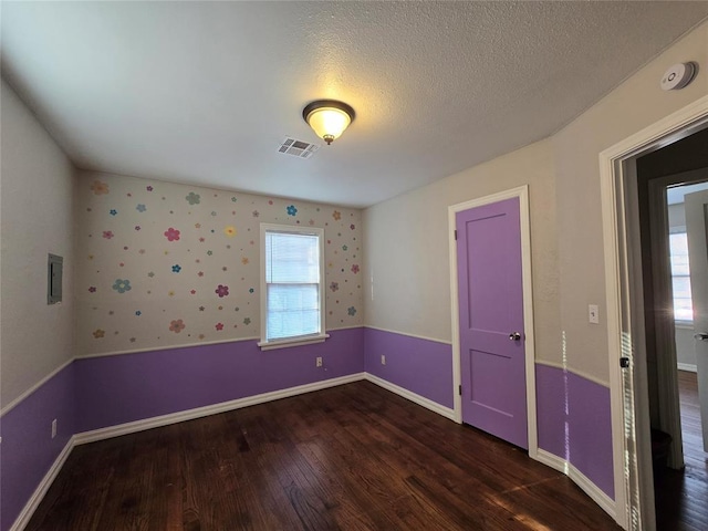 unfurnished room with wood finished floors, visible vents, a wealth of natural light, and a textured ceiling