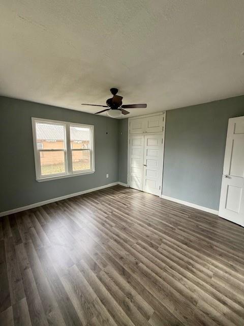 unfurnished bedroom with ceiling fan, a textured ceiling, dark wood-type flooring, and baseboards