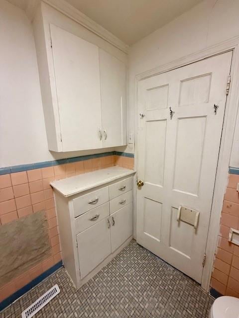 kitchen with visible vents, white cabinetry, tile walls, and light countertops