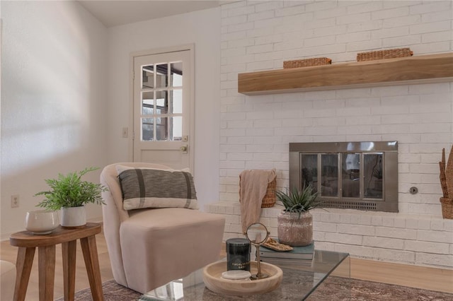 sitting room featuring a brick fireplace and wood finished floors